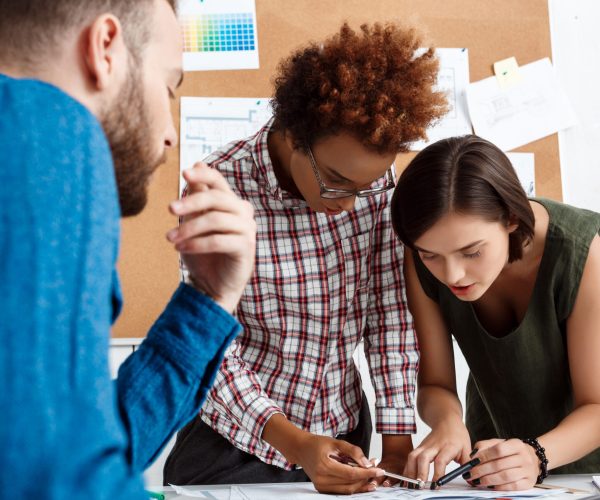 Colleagues smiling, speaking, discussing drawings, new ideas in office